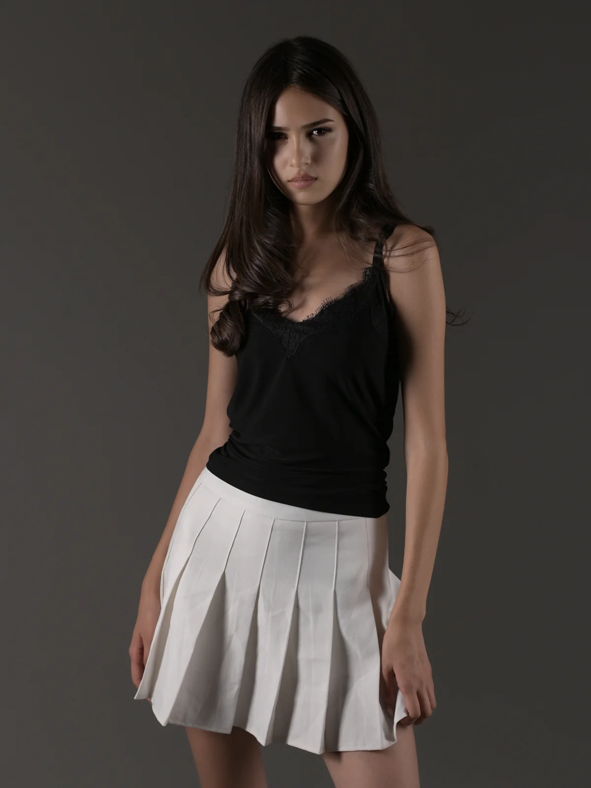 Anano modeling a black top and white pleated skirt in a Tbilisi studio