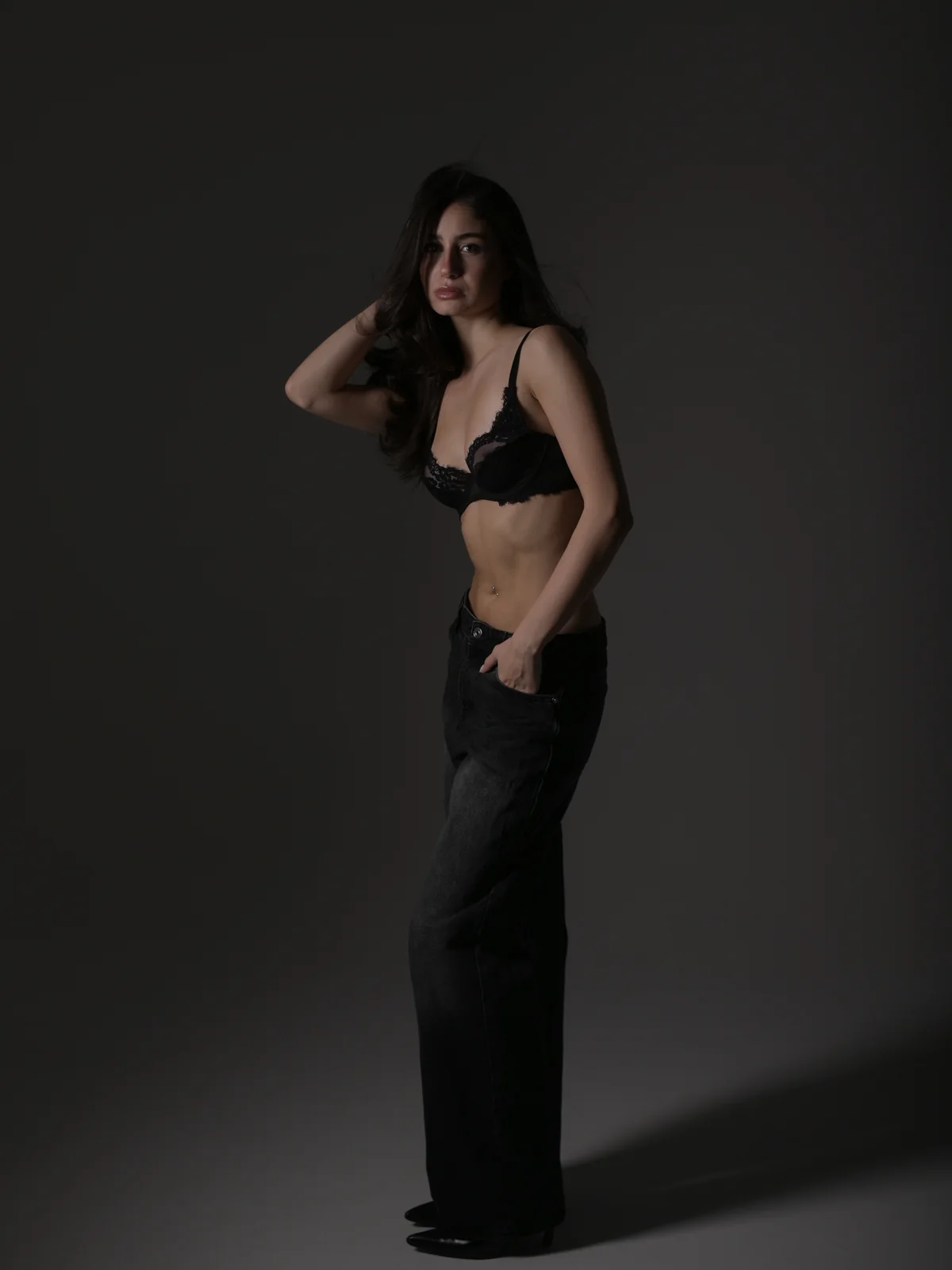 Full-body studio photo of Mari posing in a black lace top and black flared jeans