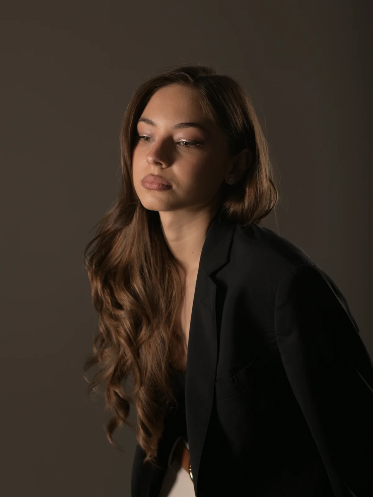 მეგანის ახლო fashion პორტრეტი შავი პიჯაკით ნეიტრალურ სტუდიურ ფონზე