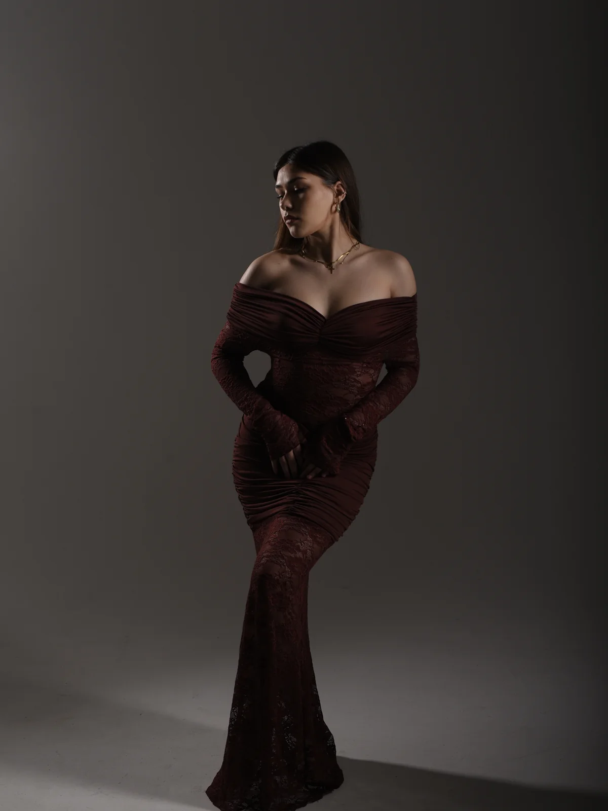 Full-length portrait of Mariam in an off-shoulder burgundy lace gown