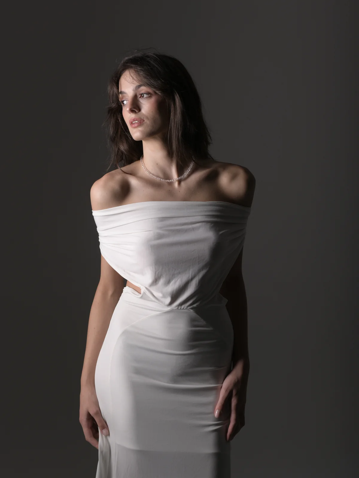 Dramatic studio portrait of Qeti in a white strapless dress with a pearl necklace