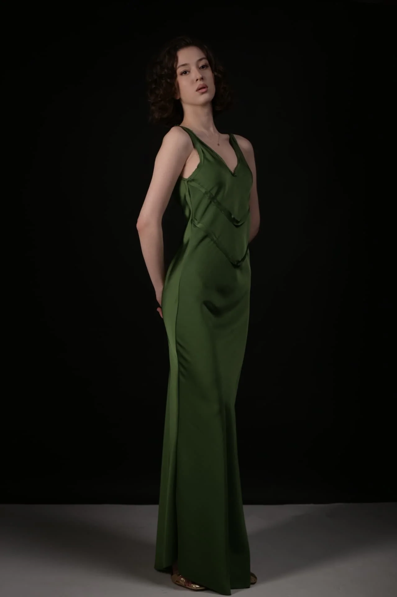 Lizi modeling a green evening dress against a black studio background