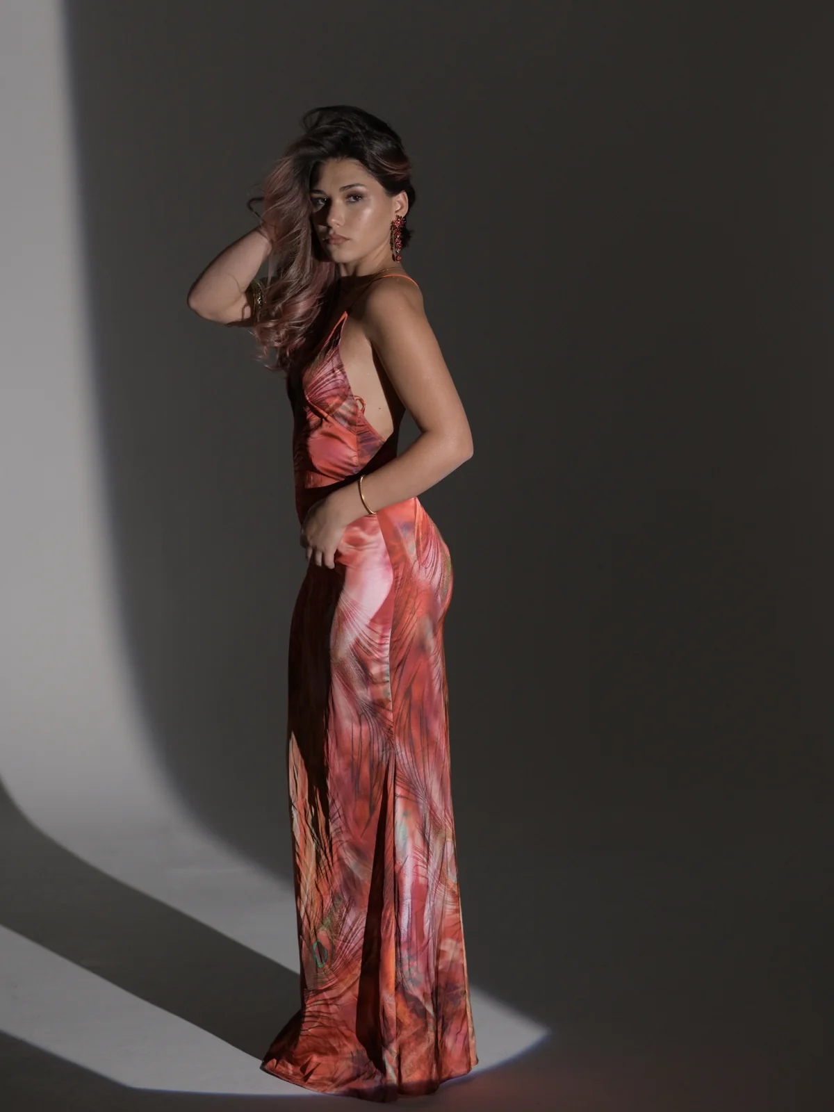 Full-length fashion portrait of Mariam in a red patterned maxi dress under dramatic studio light