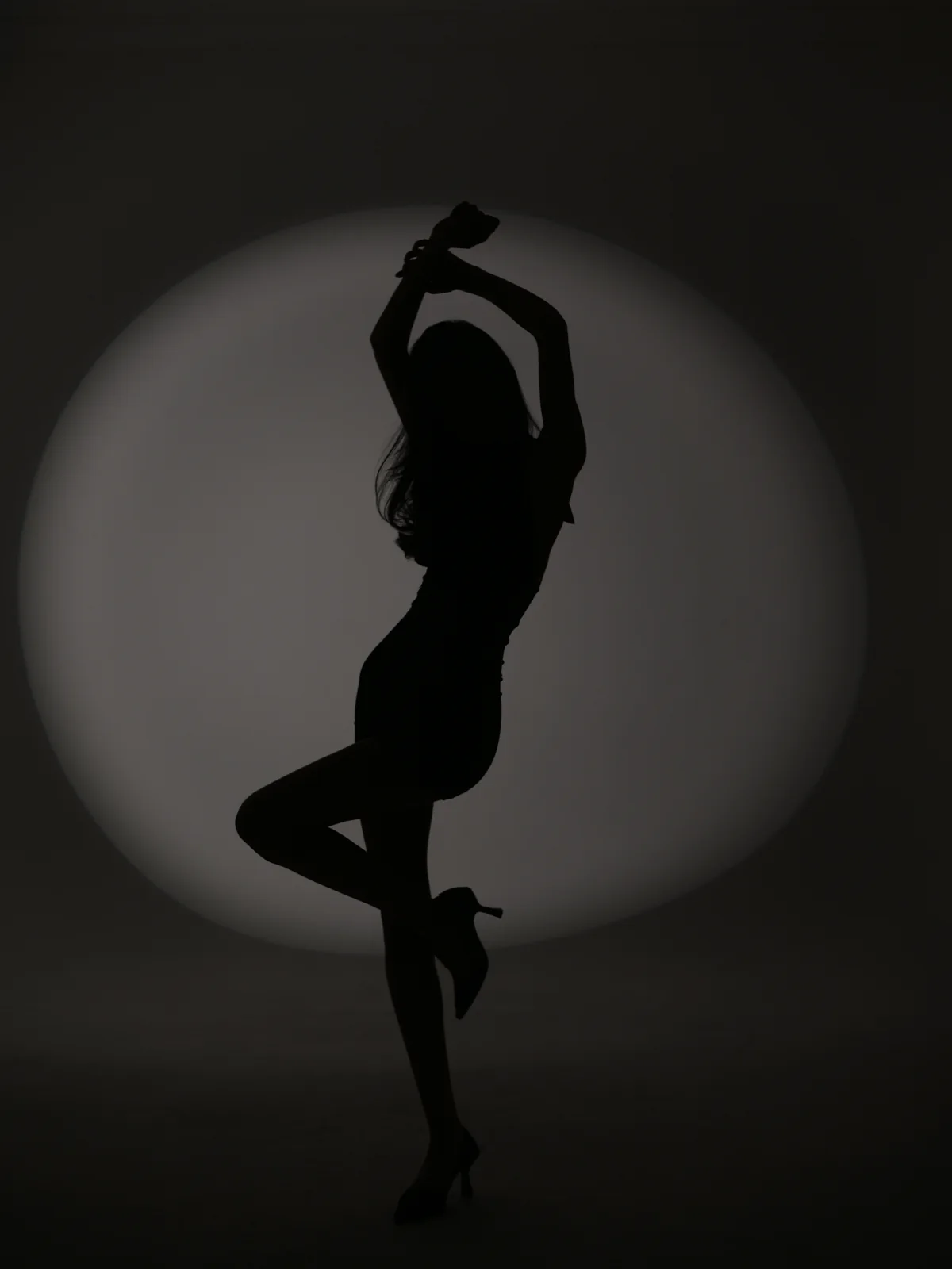 Artistic silhouette of Anano posing against a circular studio spotlight