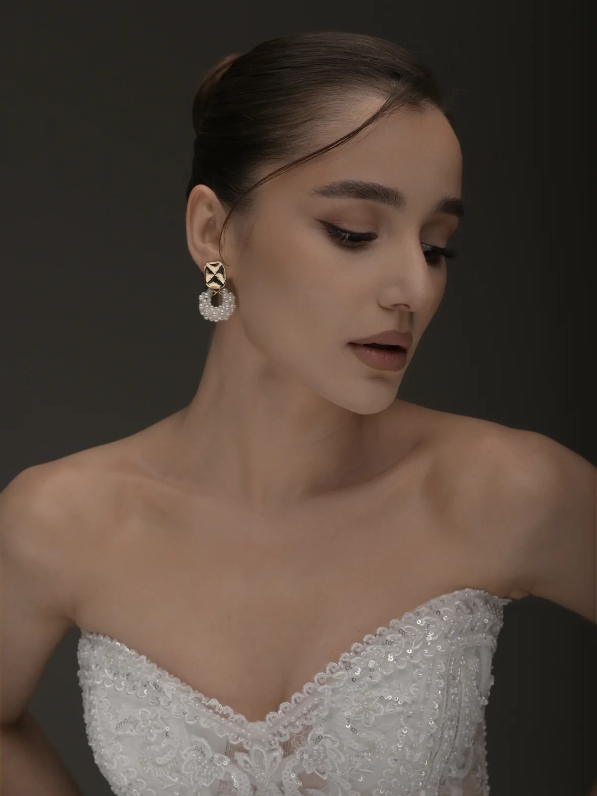 Close beauty portrait of Ninia wearing statement earrings under soft studio light