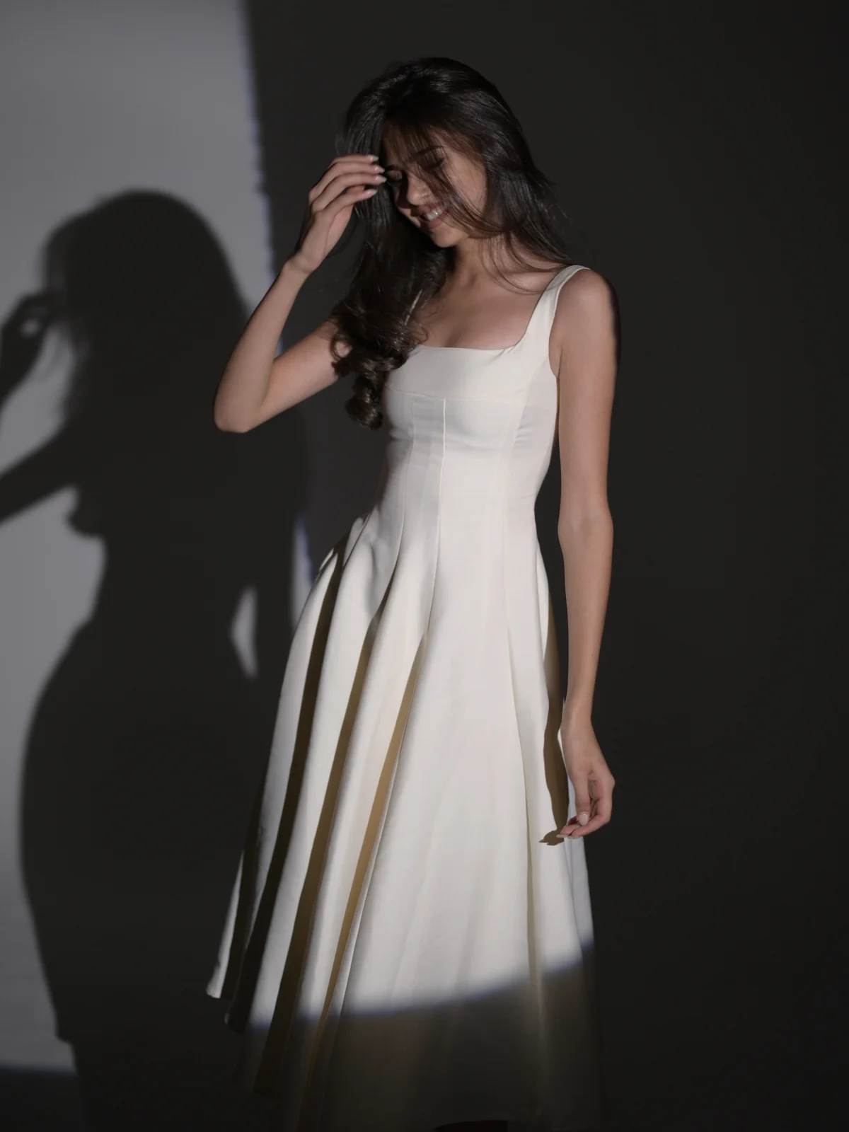 Anano in a white dress framed by geometric light and shadow in a photo studio