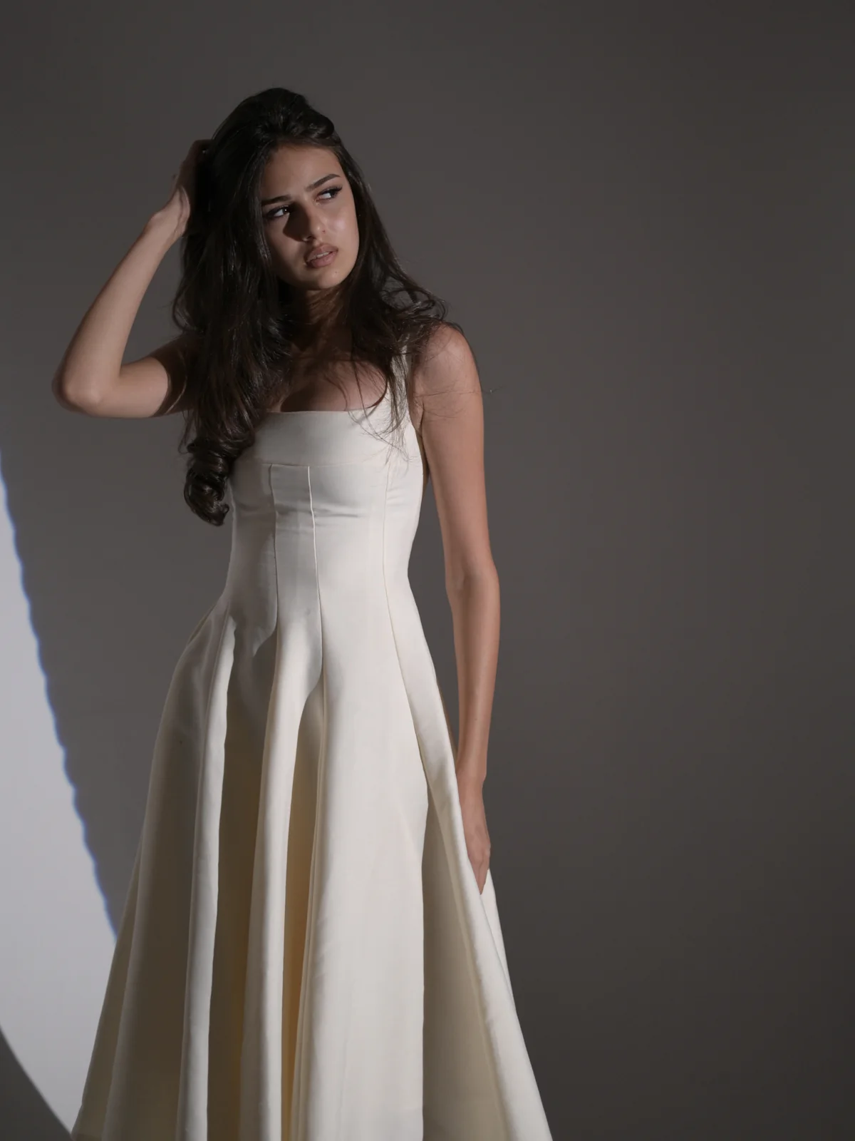 Full-length fashion portrait of Anano in a white dress under dramatic studio light