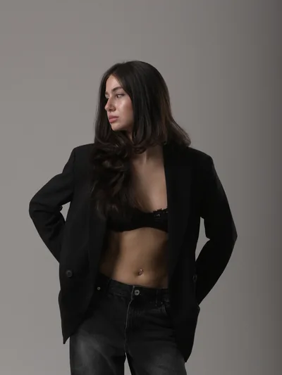Fashion portrait of Mari in an open black blazer, lace top and black jeans in a Tbilisi studio