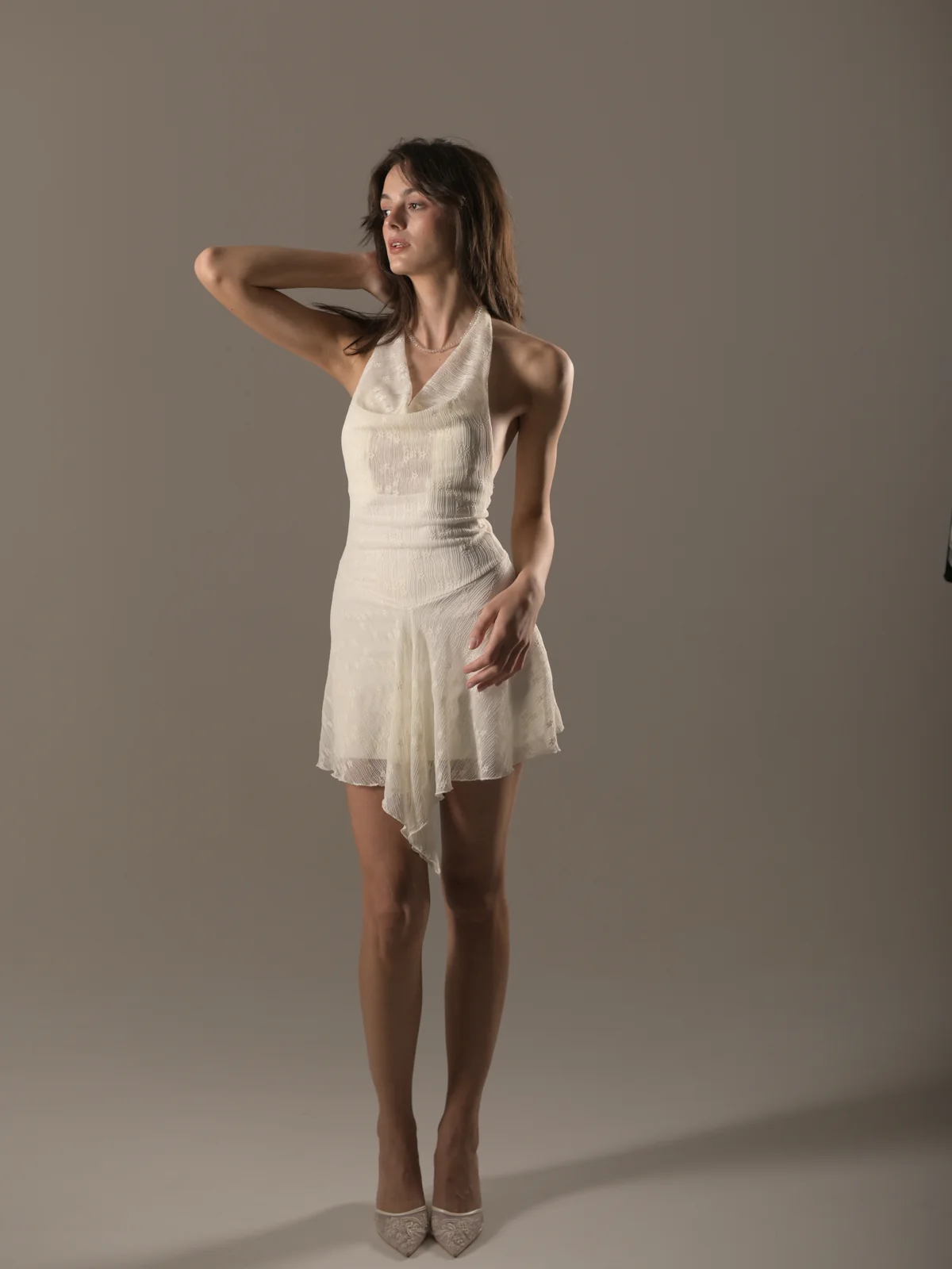 Fashion portrait of Qeti in an ivory halter dress running a hand through her hair