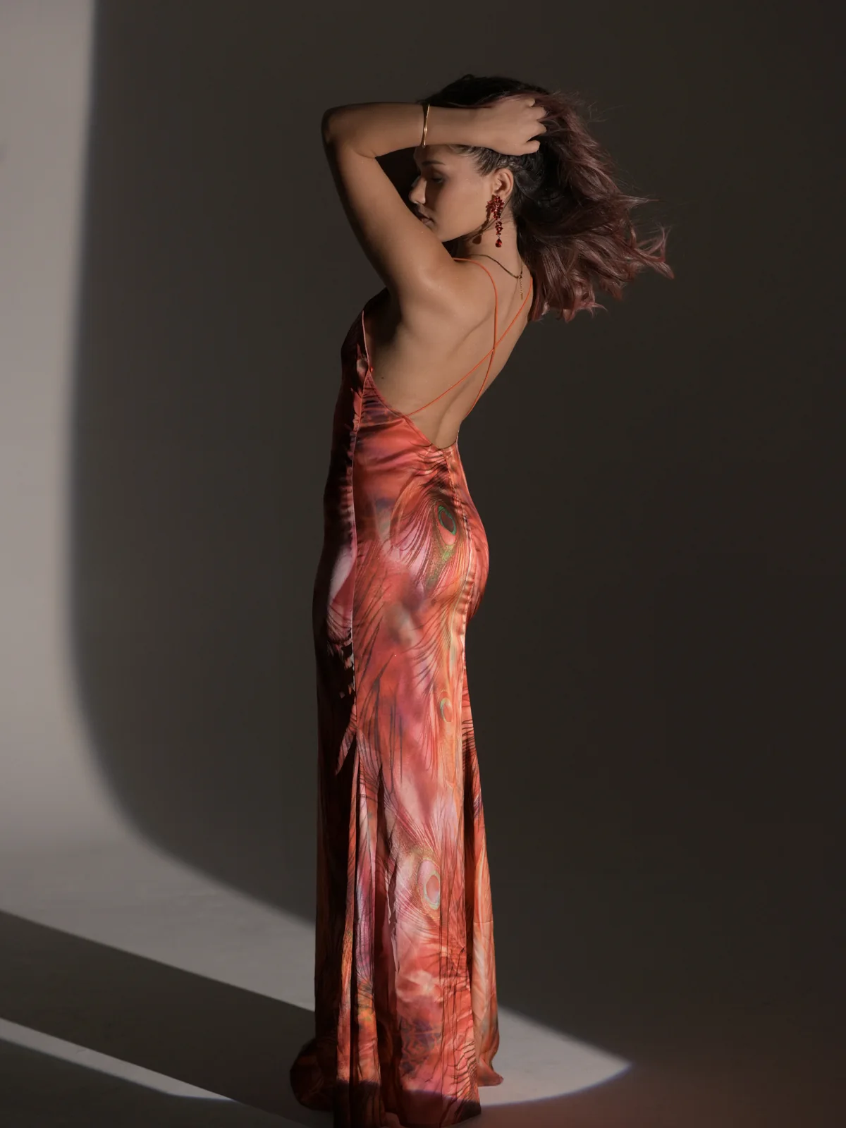 Back view of Mariam in a red-orange backless maxi dress during an editorial photoshoot